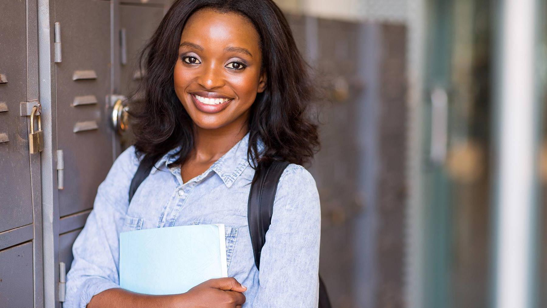 Student smiling with folder near lockers